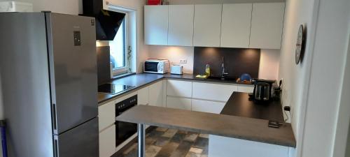 uma cozinha com armários brancos e um frigorífico de aço inoxidável em Dingsbums em Unteraichwald
