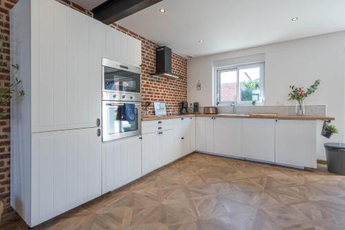 a kitchen with white cabinets and a brick wall at L'annexe Morbecque in Morbecque