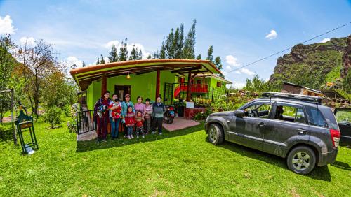 eine Gruppe von Menschen, die vor einem Haus mit einem Auto stehen in der Unterkunft Happy Land Valle Sagrado in Urubamba