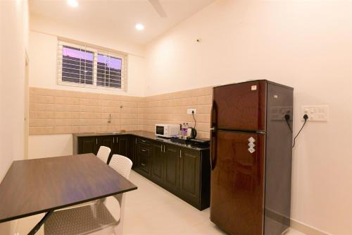 マイソールにあるXcel Luxury Hotel Apartments-Home Living Redefinedのキッチン(黒い冷蔵庫、テーブル付)