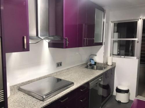 a kitchen with purple cabinets and a sink at CASA NOUR con parking in Elche