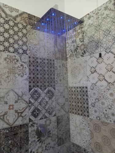 a bathroom with a shower with a tiled wall at La Mariola Apartments in Santa Luce