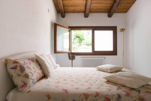 a white bedroom with a bed with a window at CA' DEL CORDER - A secret corner of peace in Venice