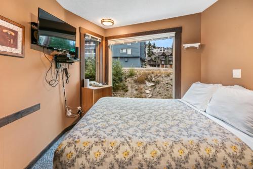 a bedroom with a bed and a tv and a window at Cozy Corner - Whitefoot Lodge 126 in Big White