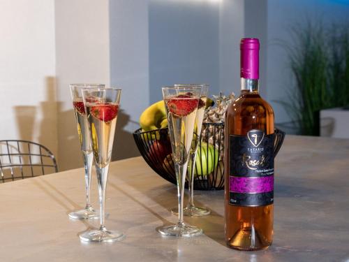 a bottle of wine and three champagne glasses on a table at Villa Stergos in Kremasti