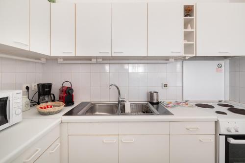 a kitchen with white cabinets and a stainless steel sink at Aeginia 2 in Perdhika