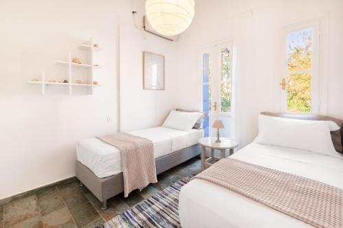 two beds in a room with white walls and windows at Aeginia 2 in Perdika