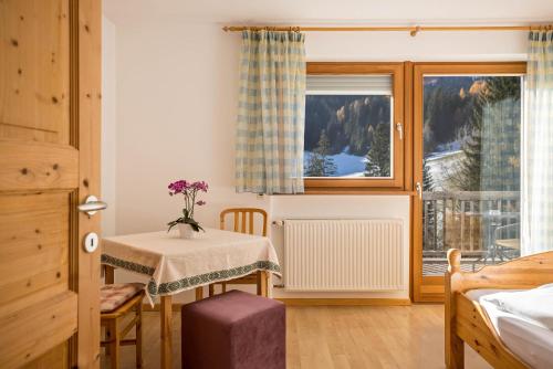 um pequeno quarto com uma mesa e uma janela em Bnb Lettnerhof Balcony Family Suite em Monguelfo