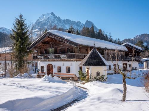 a house in the snow with mountains in the background at Hotel Jagdschlössl in Kirchdorf in Tirol