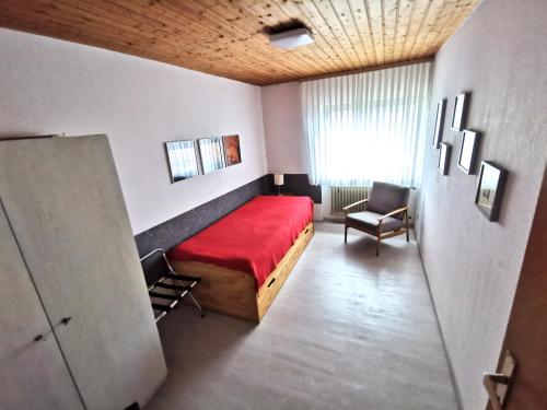 a bedroom with a red bed and a chair at Ferienwohnung Sinsheim-Dühren in Sinsheim
