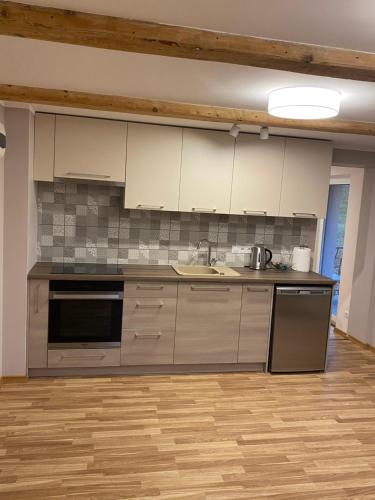 a kitchen with stainless steel appliances and wooden floors at Saules iela 2A in Saldus