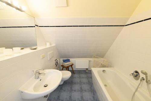 a bathroom with a sink and a toilet and a tub at Ferienwohnung 7 mit Wasserblick, Balkon 2 Pers in Neuenkirchen