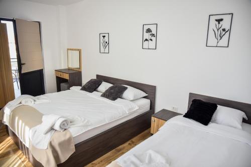 two beds in a room with white walls at Casa YDA in Horezu