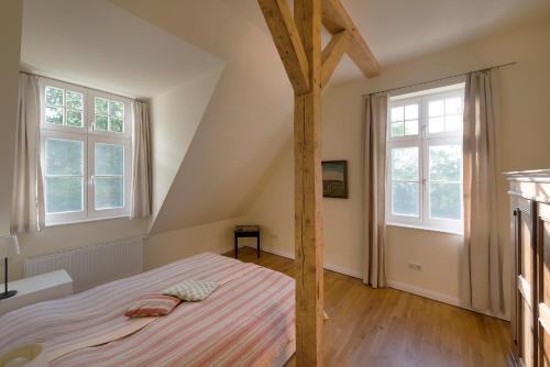 a bedroom with a bed and two windows at Ferienwohnung 7 mit Wasserblick, Balkon 2 Pers in Neuenkirchen