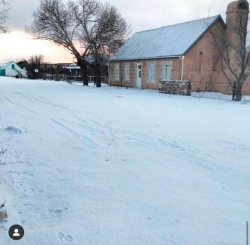 a snow covered field with a building and a barn at Die Tabakhuis - Karoo (Sutherland) in Sutherland
