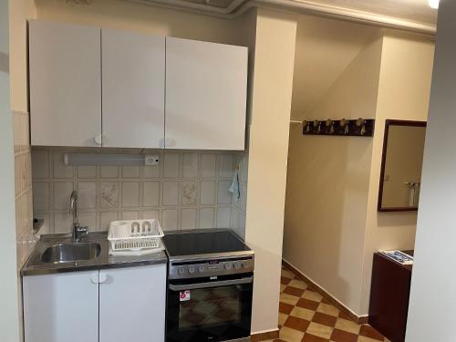 cocina con armarios blancos, fregadero y fogones en Apartments Leko, en Portorož