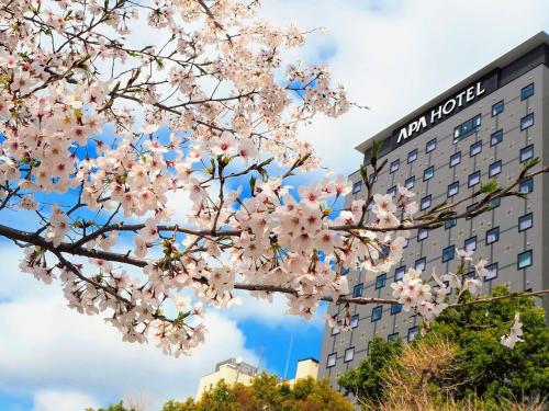 a tree with pink flowers in front of a building at APA Hotel Keisei Ueno Ekimae in Tokyo