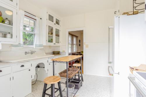 ホノルルにあるGarden Cottage Unit Bの白いキャビネット、テーブル、スツール付きのキッチンが備わります。