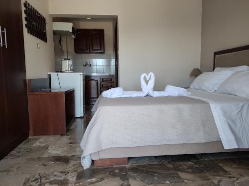 a bedroom with a large white bed with a kitchen at Gregory Apartments in Tolo