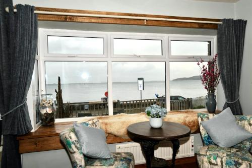 a living room with a large window with a view of the ocean at Sea View Guest House in Benllech