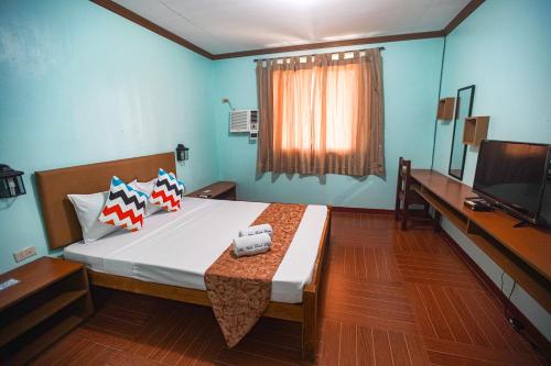 Schlafzimmer mit einem Bett, einem Schreibtisch und einem TV in der Unterkunft Isla Vista Beach Resort in Candelaria