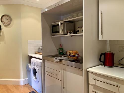 a kitchen with a washing machine and a microwave at Southernwood - West Wing in Didcot