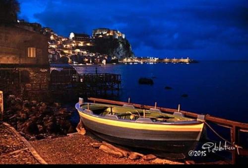 a boat sitting on the shore of the water at night at Al Quindici Scilla in Scilla
