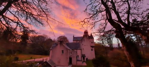 an old white house with a sunset in the background at East Wing Lickleyhead Castle in Auchleven