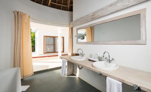 a bathroom with two sinks and a large window at Gold Zanzibar Beach House & Spa in Kendwa