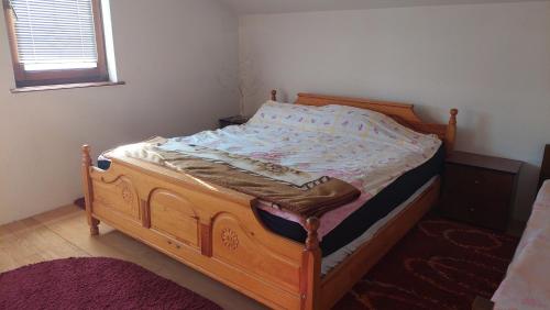 a wooden bed in a bedroom with a window at Mini Farm Adi in Cazin