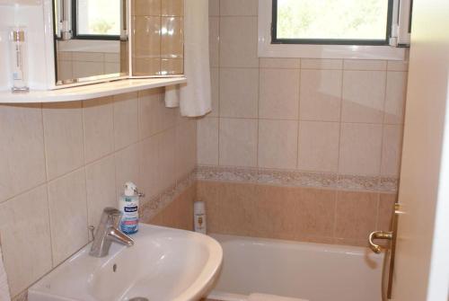 Alexandra's Apartment في كالاميتسي: حمام مزود بمغسلة وحوض استحمام ومغسلة