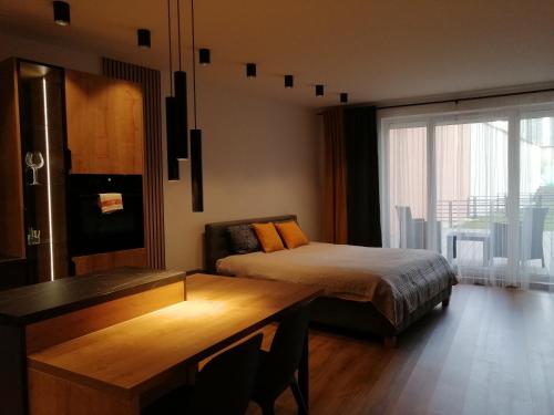 a bedroom with a bed and a desk and a window at Apartament River House in Szczecin