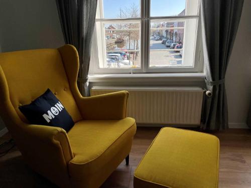 un salon avec une chaise jaune et une fenêtre dans l'établissement Ferienwohnung Hafensicht 25507, à Weener