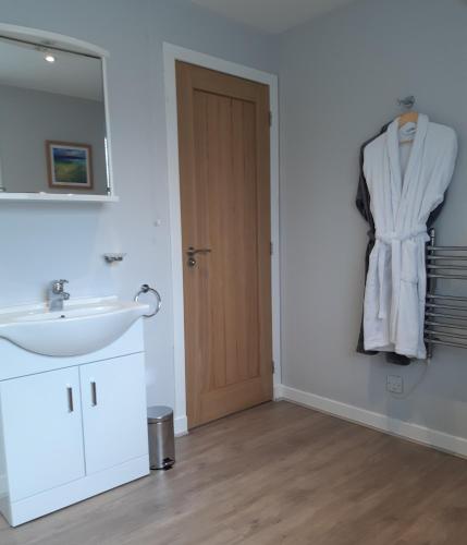 a bathroom with a sink and a mirror and a door at Caisteal Liath in Lochinver