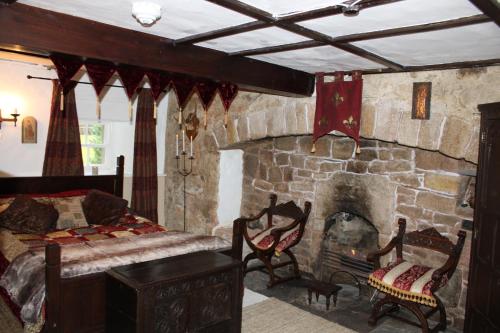 a bedroom with a stone fireplace with a bed and chairs at East Wing Lickleyhead Castle in Auchleven