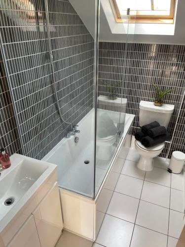 a bathroom with a tub and a toilet and a shower at The Apartment at St Georges Terrace in Cheltenham