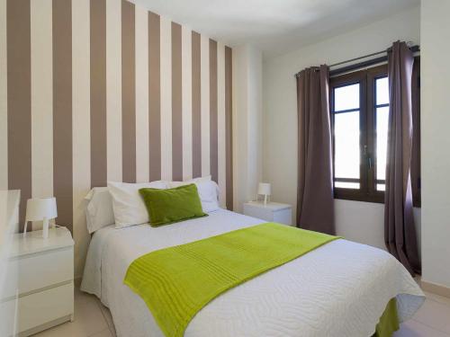 1 dormitorio con 1 cama con manta verde y ventana en Mahostly Apartamento Comillas SC, en Arrecife