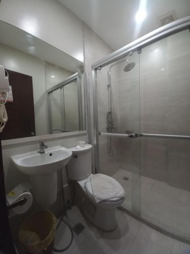 uma casa de banho com um chuveiro, um WC e um lavatório. em Holiday Suites em Puerto Princesa