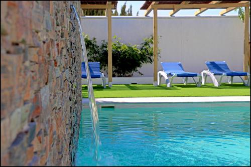 a pool with blue chairs and a water fountain at Bungalow La Roa V in Conil de la Frontera