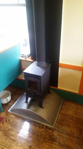 a stove in the corner of a room at The Megabus near Tavistock and Dartmoor. in Lamerton