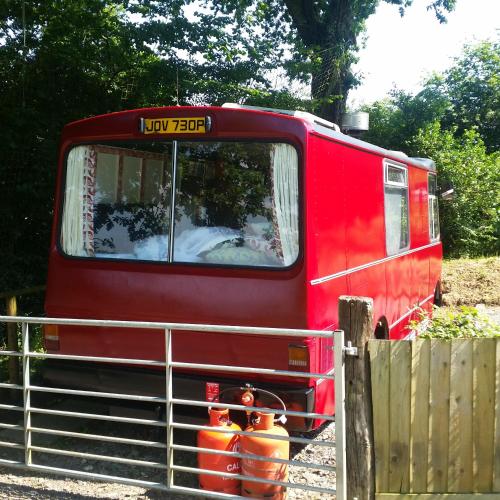 a red train is parked next to a fence at The Megabus near Tavistock and Dartmoor. in Lamerton