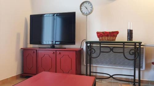 a tv on a red cabinet with a clock on the wall at Le Gîte des Templiers à Montfort-sur-Argens in Montfort-sur-Argens