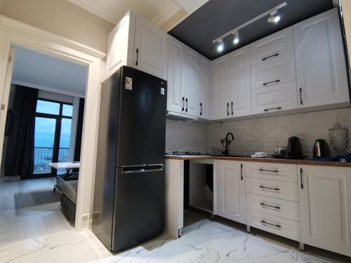 a kitchen with white cabinets and a black refrigerator at Sumqayıt bulvarı in Sumqayıt