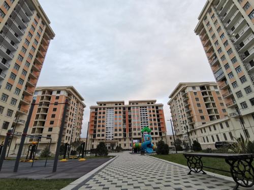 two tall buildings with a playground in the middle at Sumqayıt bulvarı in Sumqayyt