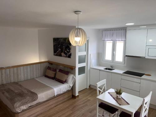 a bedroom with a bed and a table and a kitchen at APARTAMENTO , LOFT BOBASTRO CErCA DEL CAMINITO DEL REY ARDALES in Ardales