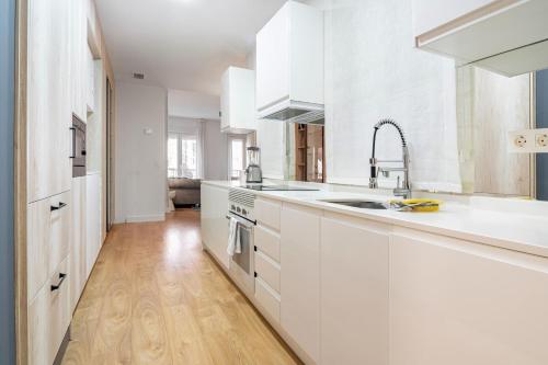 a kitchen with white cabinets and a wooden floor at 3 bedrooms 2 bathrooms furnished - Salamanca - Stylish - MintyStay in Madrid