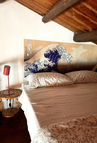 a bed with a large blue and white painting on the wall at Loft Aragonese in Palermo