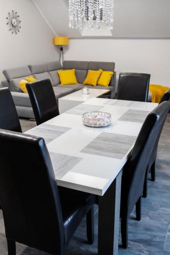 a dining room with a table and chairs and a couch at Apartamenty ASLux - Noclegi Energylandia Zator in Zator