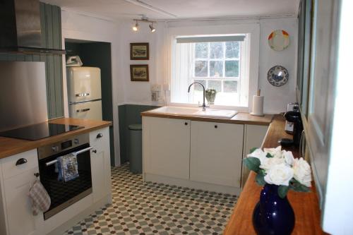 a kitchen with white cabinets and a sink and a window at East Wing Lickleyhead Castle in Auchleven
