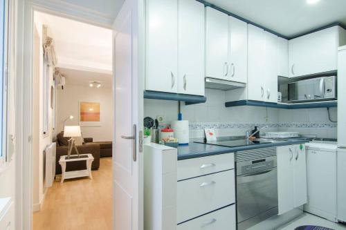 a kitchen with white cabinets and a living room at 1 bedroom 1 bathroom furnished - Chamberi - Cozy - MintyStay in Madrid